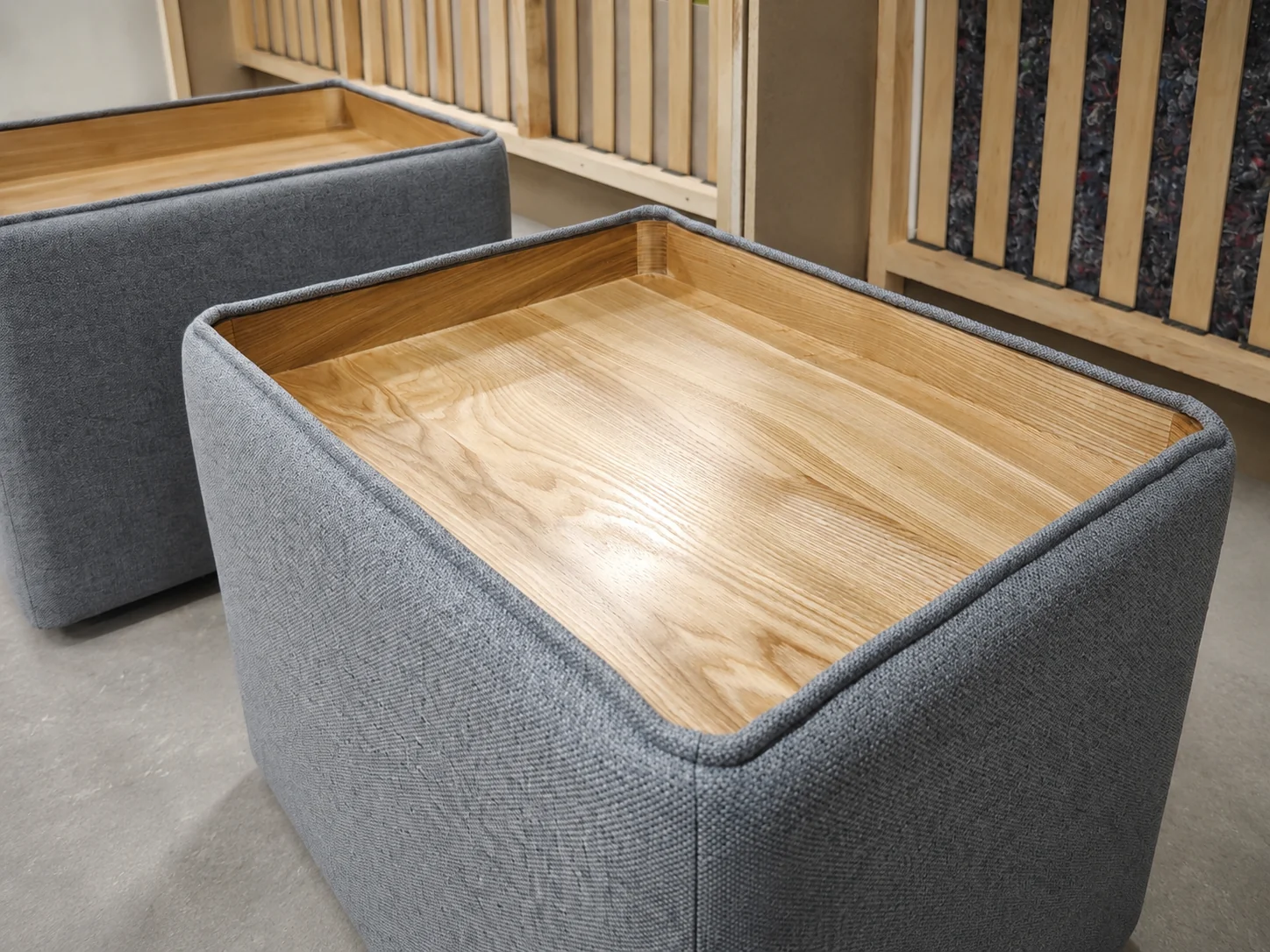 Two completed gray upholstered tables with integrated wooden trays